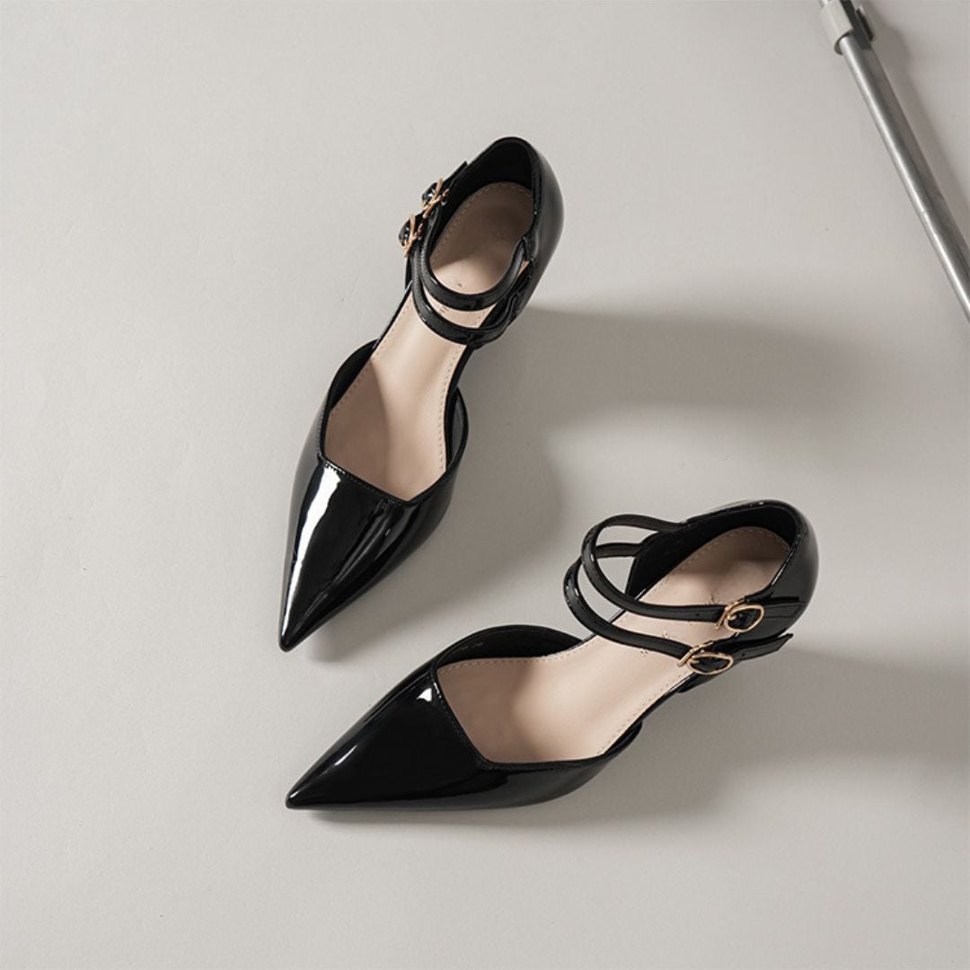Black pointed-toe shoes with thin straps on a light gray background