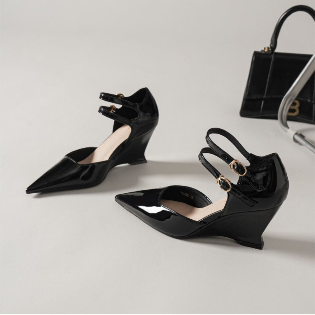 Black high-heeled shoes with bow details on a light gray background