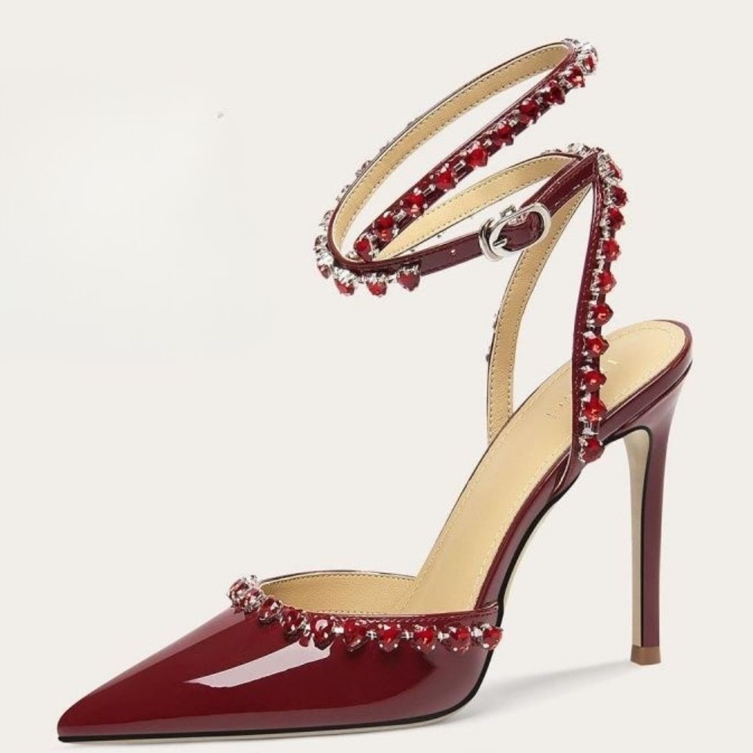 Red high-heeled shoe with embellishments on a light gray background