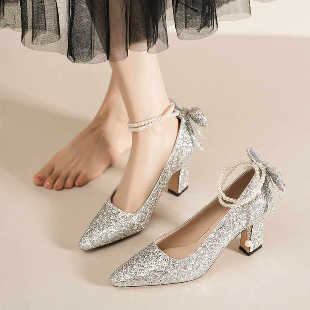 Silver glitter high heels with bow details on a neutral background