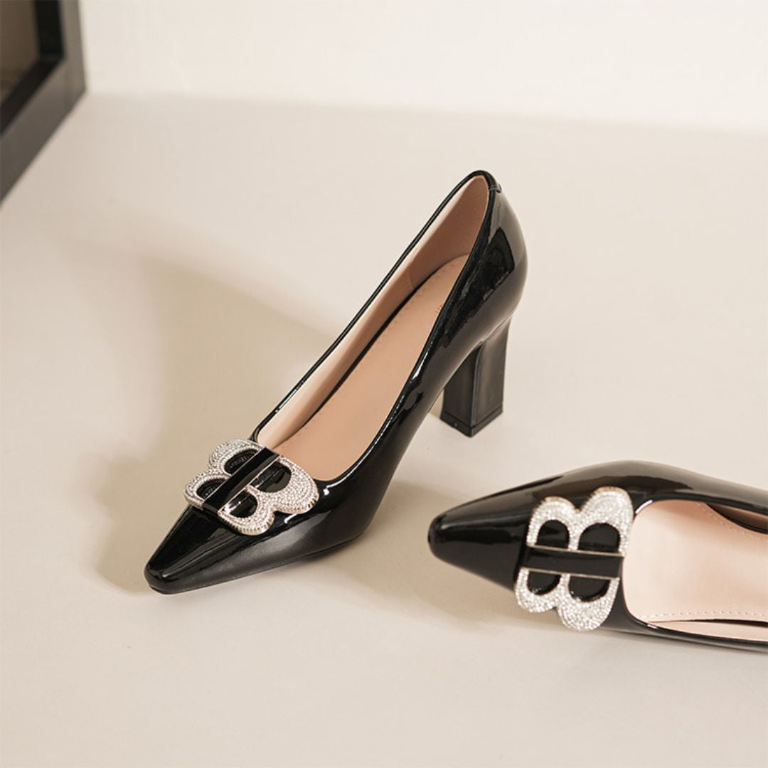 Black high-heeled shoes with decorative buckles on a light background
