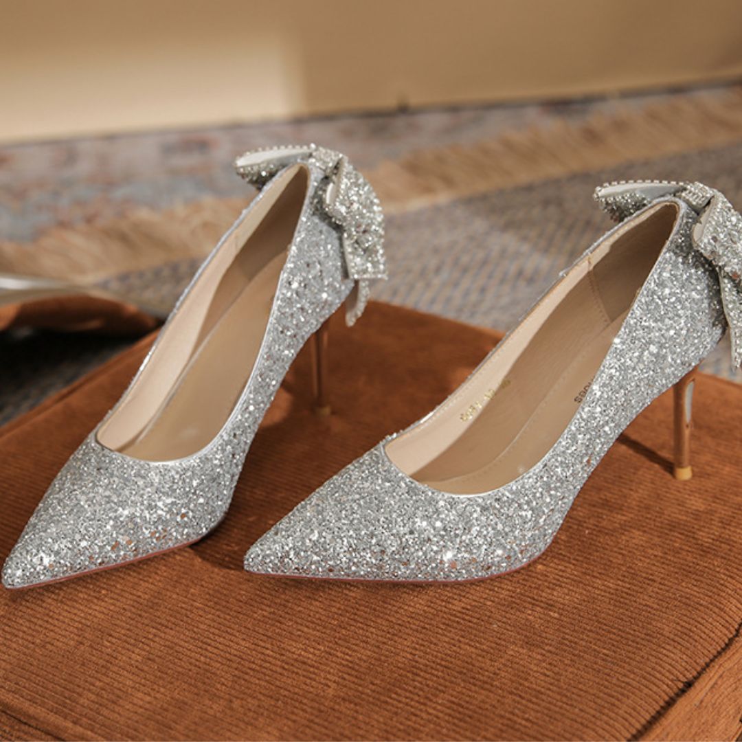 Anmol silver shimmer bridal stiletto heels with rhinestone bow - front view